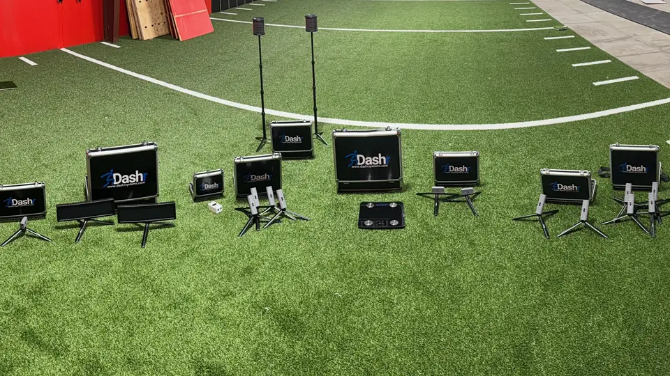 The Dashr electronic timing system laid out on the turf at Momentum: timing gates on tripods, their branded carry cases and a jump mat, with the start-line arc behind
