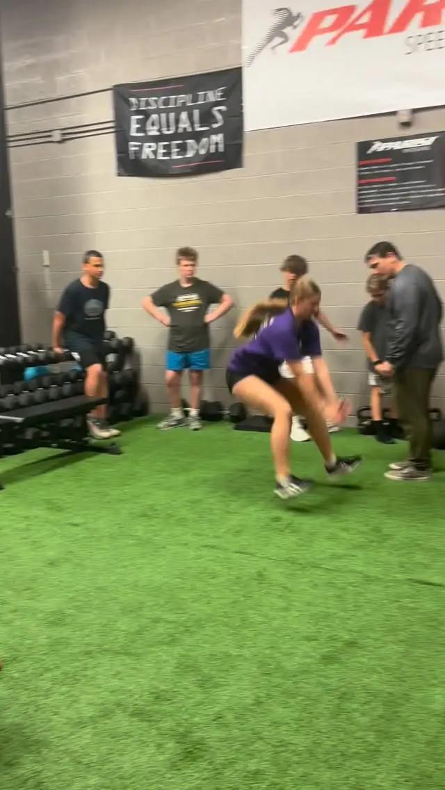 Athlete mid broad-jump landing on the green turf