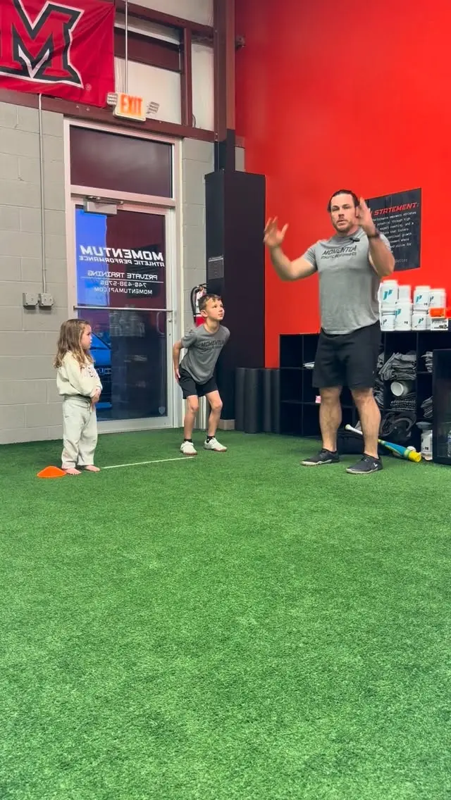 Coach demonstrating a drill to two young athletes