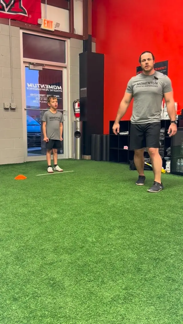 Coach leading a young athlete through a marching drill