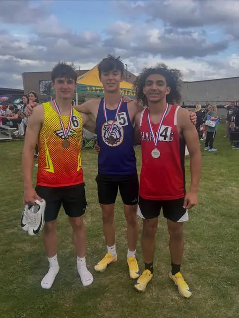 Three teen medalists arm-in-arm at an outdoor track meet