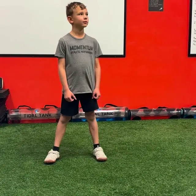 Young athlete in a Momentum tee ready on the green turf