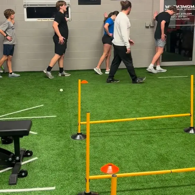 Athletes doing wall-lean acceleration drills with a coach