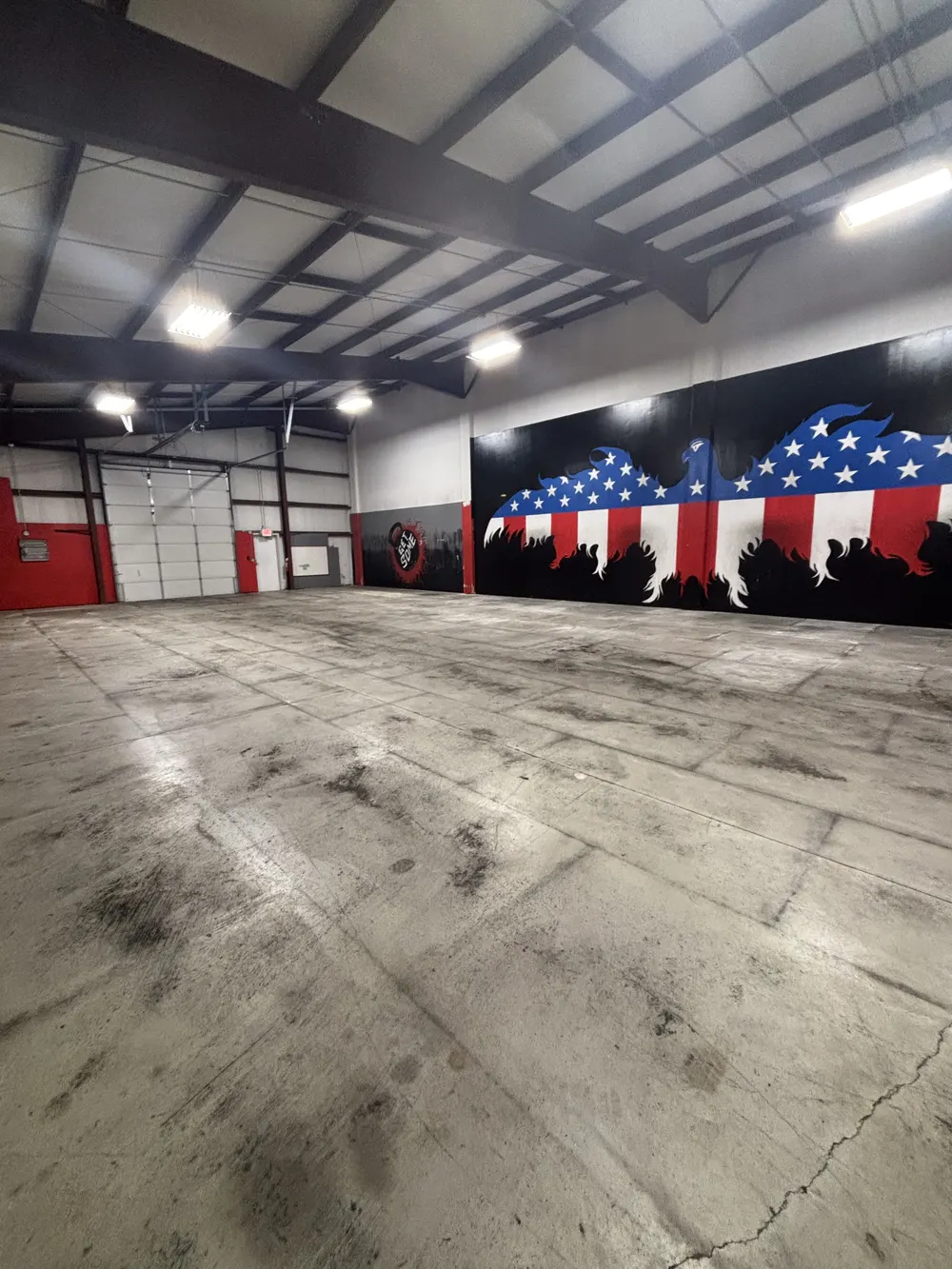 Wide view of the empty concrete floor with an American flag eagle mural painted along the black right-hand wall