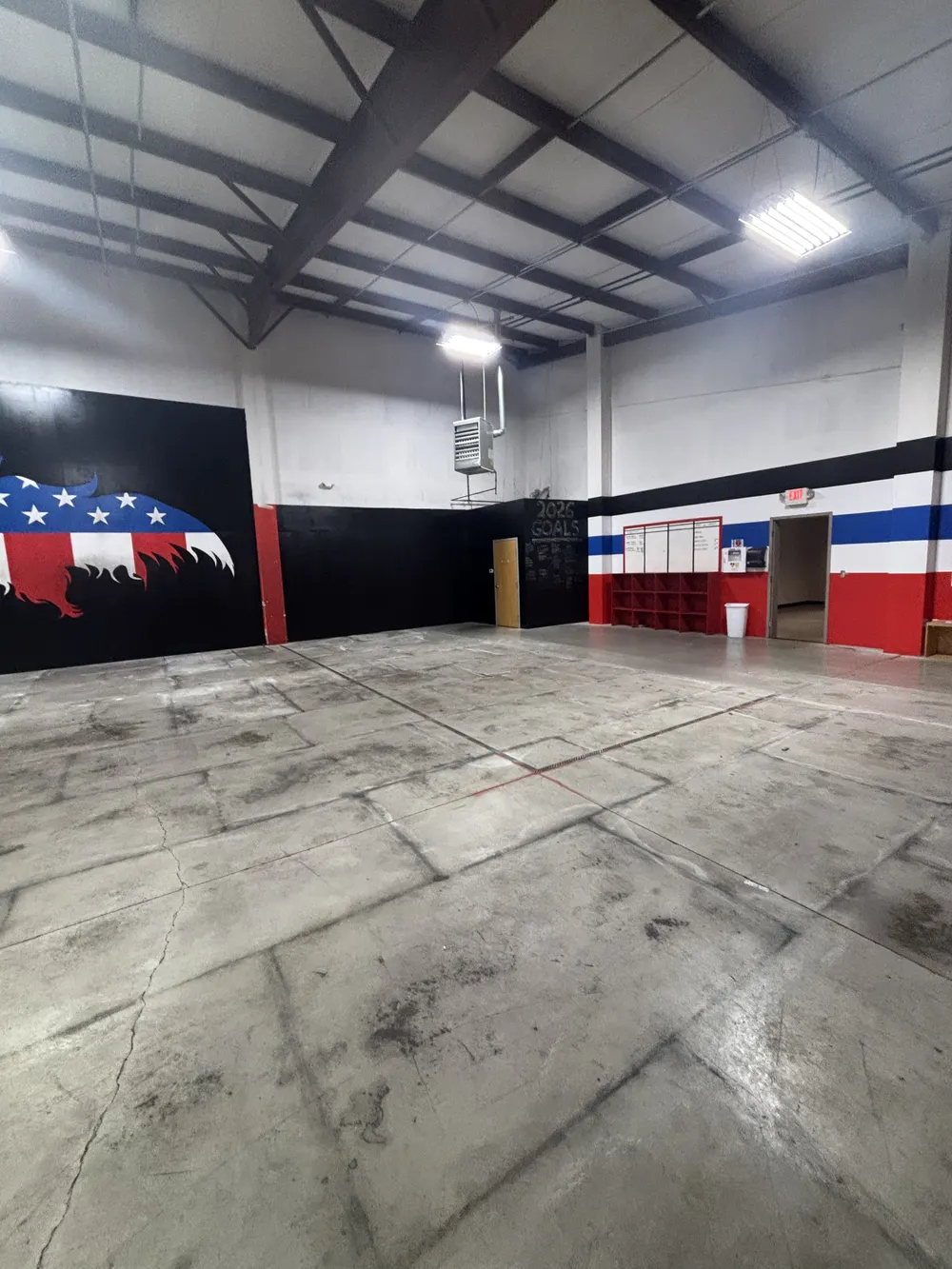 Inside the new building: a black wall with 2026 Goals written on it, red cubby shelving and a red, white and blue stripe above the doorway